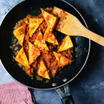 tofu triangles coated in ketchup & onion sauce in fry pan