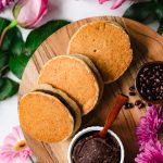 three vegan dorayaki overlapping each other on serving platter, flowers surrounding in background