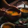 someone reaching for a spoonful of vegan kabocha soup