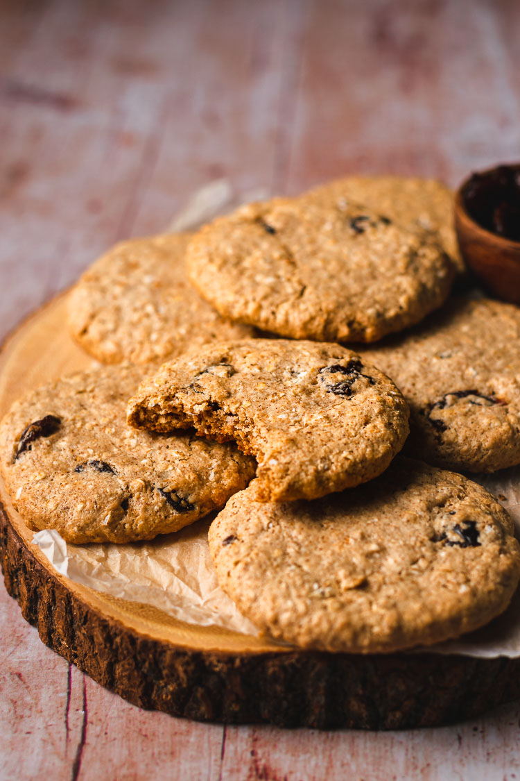 vegan oatmeal raisin cookies on a platter with a bite taken out of one