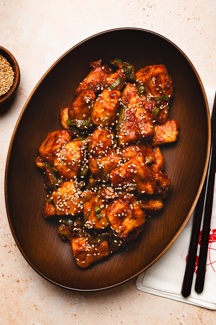 sweet and sour tofu in a bowl with chopsticks