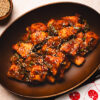 sweet and sour tofu in a bowl with a pinch bowl of sesame seeds in the corner