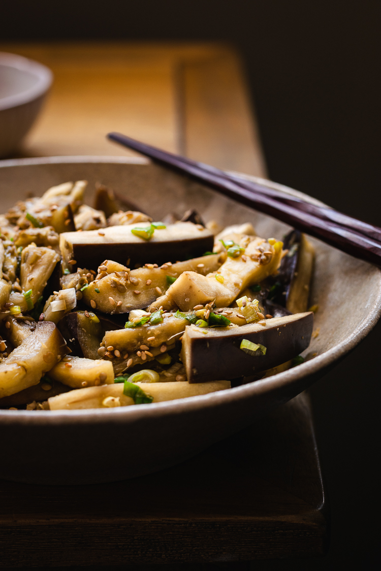 steamed eggplant with green onion dressing in a plate on the corner of a table