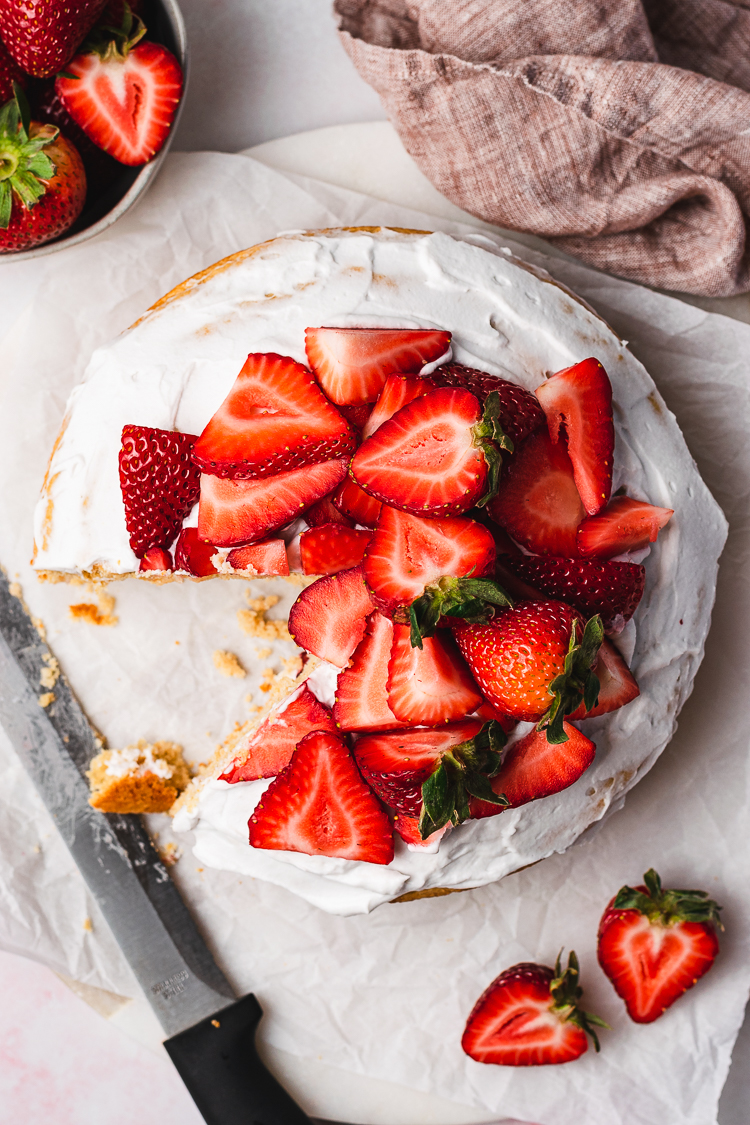 overhead shot of vegan strawberries and cream cake with a slice cut out