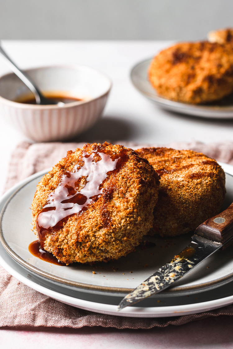 vegan korokke on a plate with sauce drizzled on top
