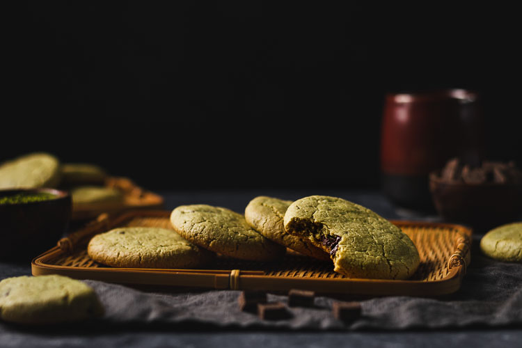 vegan matcha chocolate chunk cookies arranged on a serving platter with a bite taken out of one