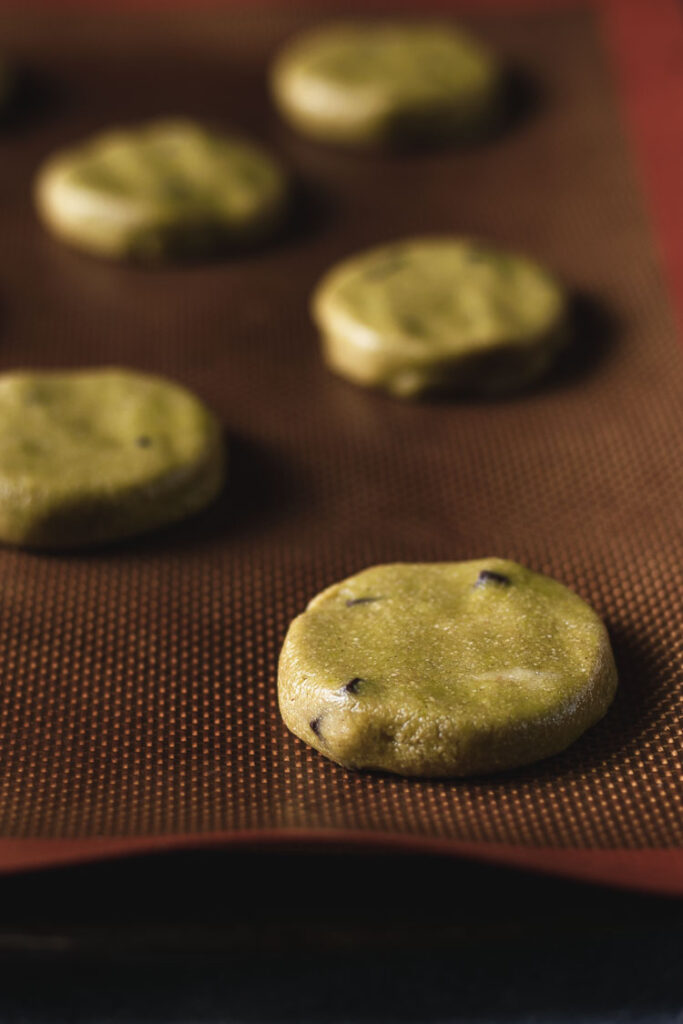 vegan matcha cookie dough discs on baking sheet before baking