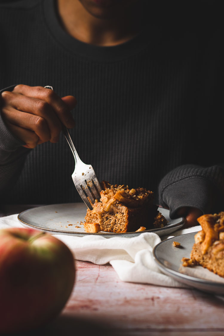 someone holding a fork to take out a bite out of a piece of cake