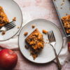 pieces of vegan apple crumb cake on two separate plates with forks, bite taken out of one piece
