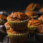 vegan pumpkin muffins stacked on top of each other, set on a wire rack