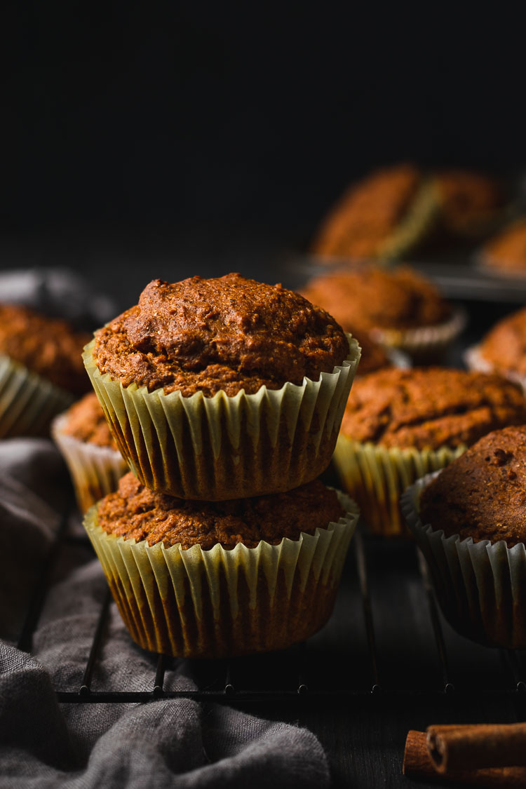 vegan pumpkin muffins stacked on top of each other, set on a wire rack