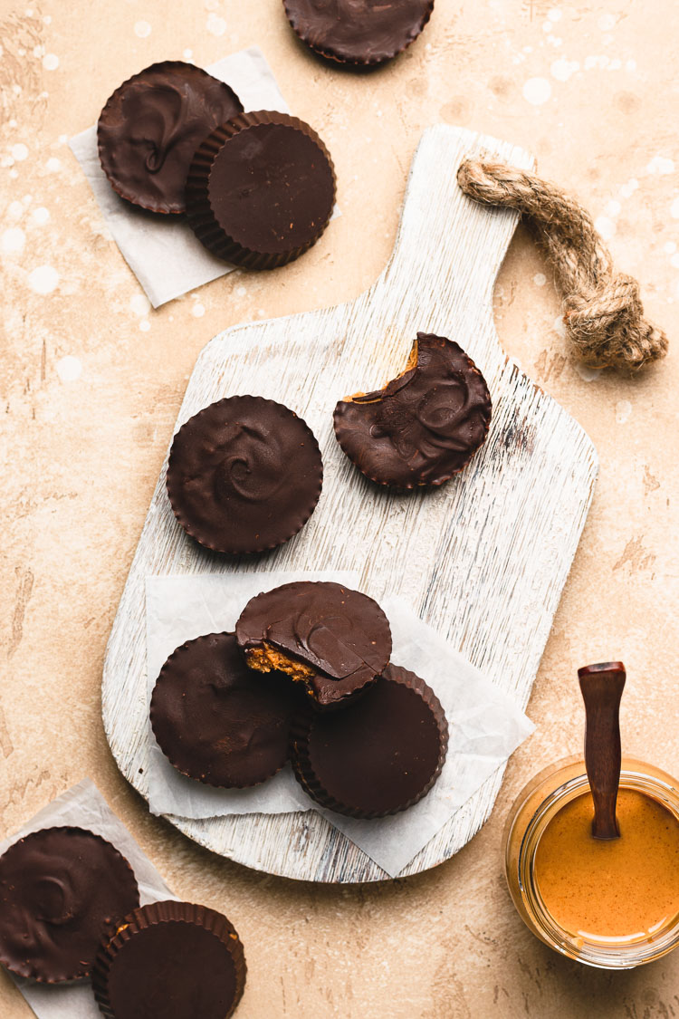 flatlay of homemade peanut butter cups, jar of peanut butter in bottom corner