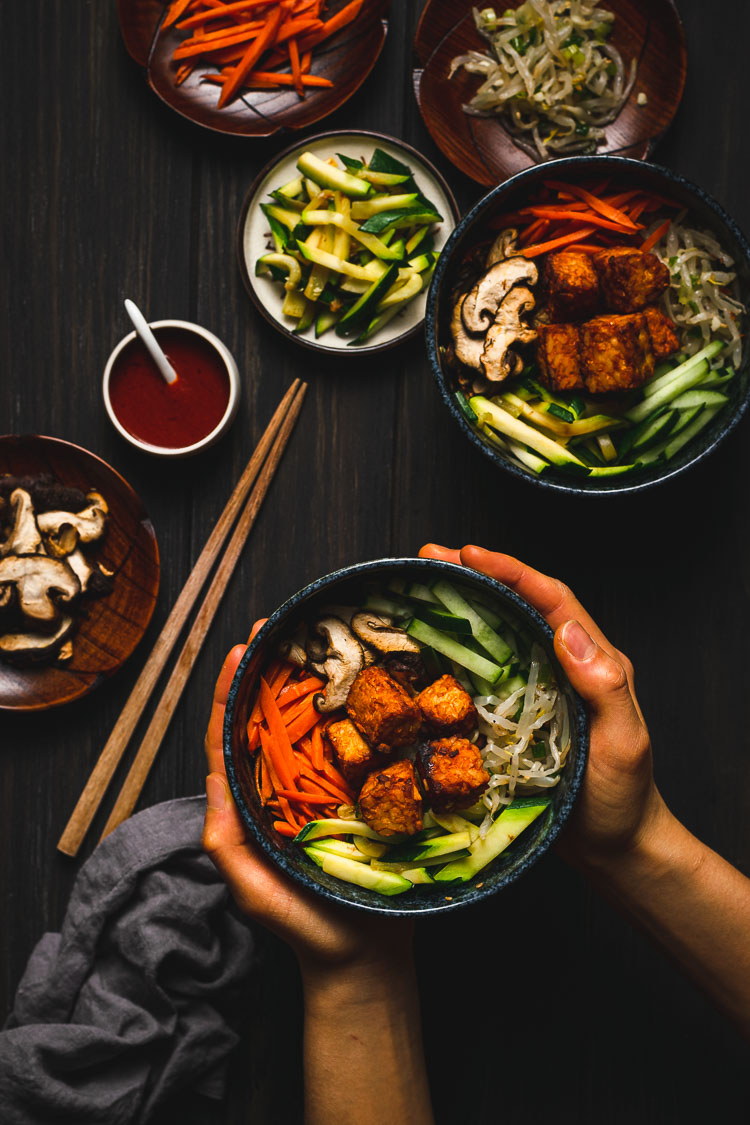 hands holding a bowl of tempeh bibimbap