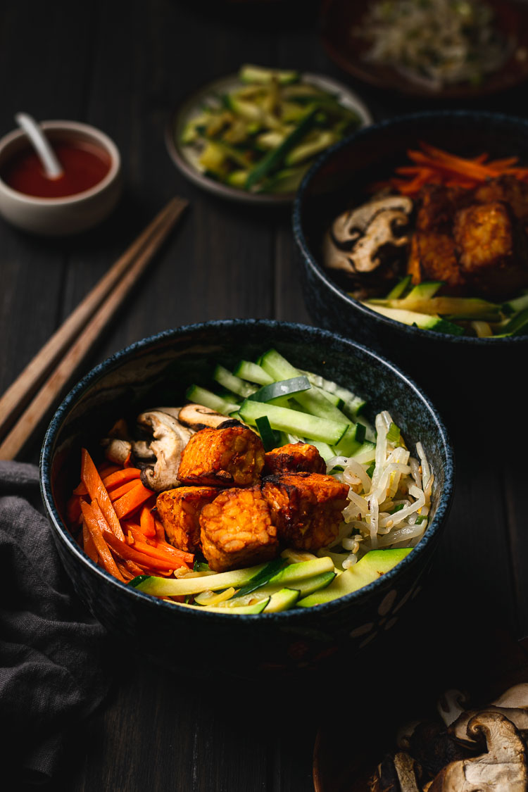 a bowl of tempeh bibimbap with ingredients in background