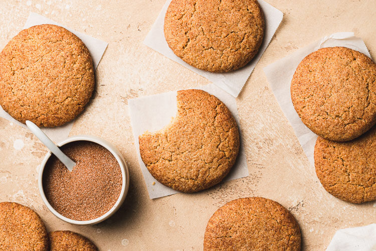 vegan gluten free snickerdoodle with a bite taken out of it, surrounded by more snickerdoodles