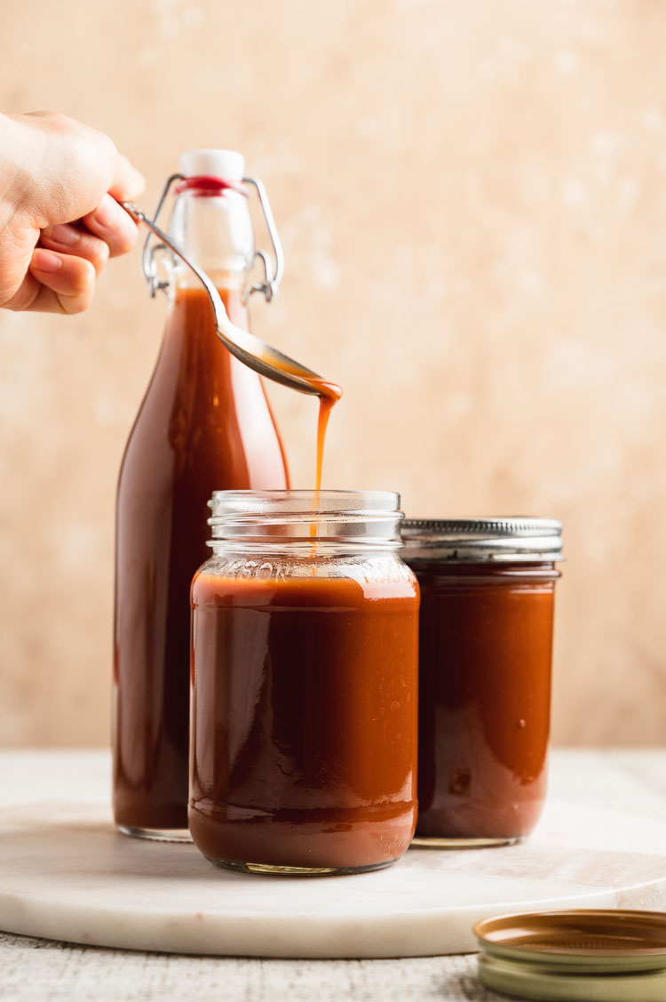 a spoonful of japanese worcestershire sauce being poured into a jar