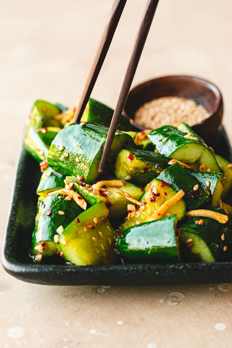 chopsticks picking up a piece of smashed cucumber