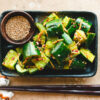 japanese smashed cucumbers on a plate with a pinch bowl of sesame seeds