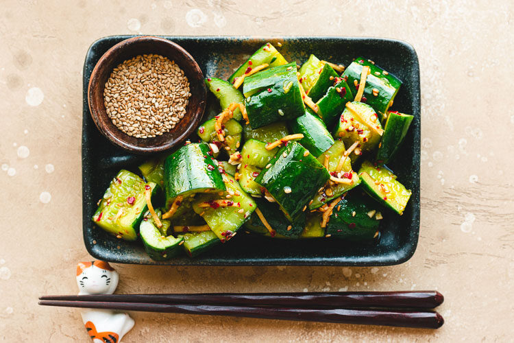 japanese smashed cucumbers on a plate with a pinch bowl of sesame seeds