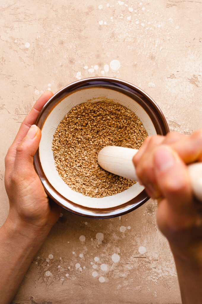 sesame seeds being ground with pestle and mortar