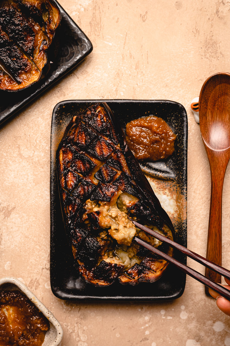 chopsticks scooping out flesh of miso eggplant