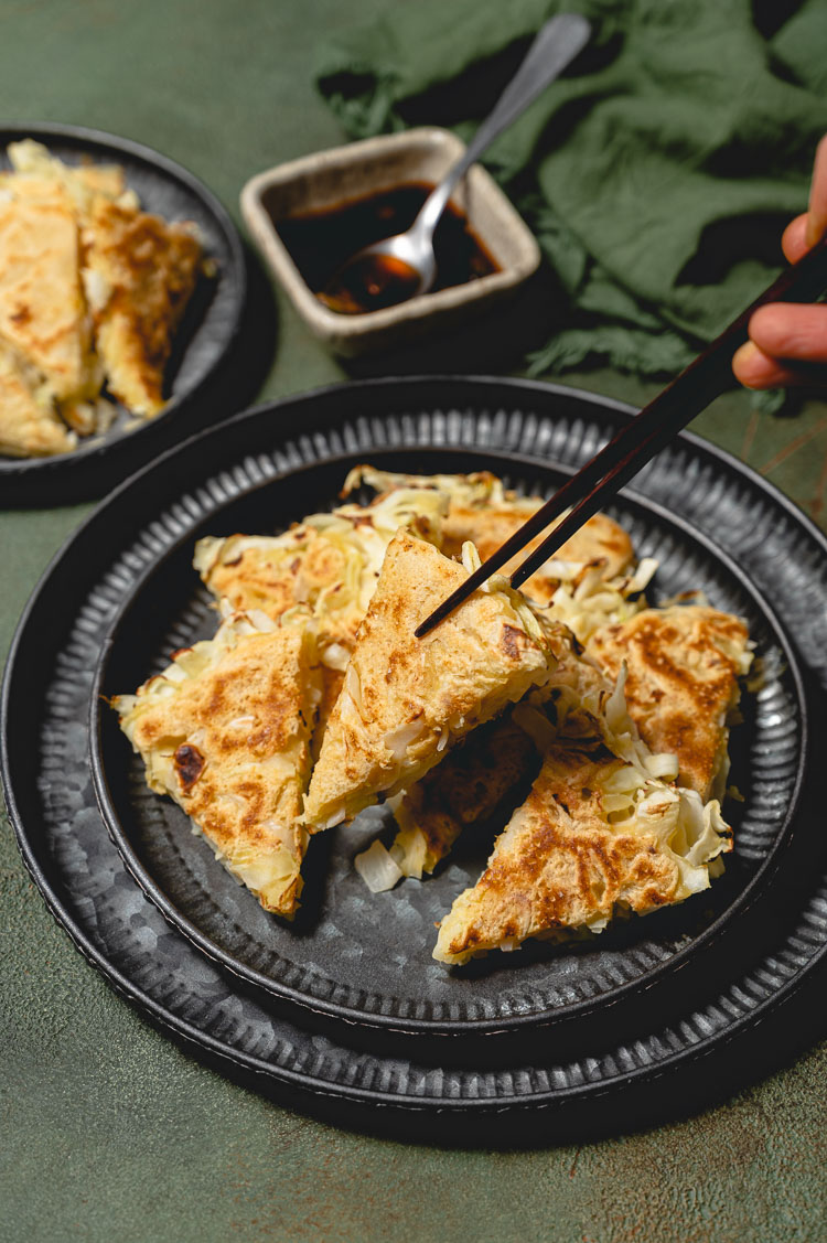 chopsticks picking up a cabbage pancake piece