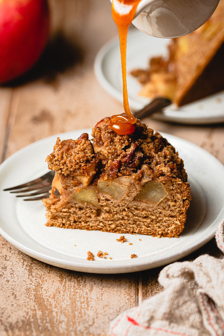 caramel being drizzled on a slice of caramel apple cake