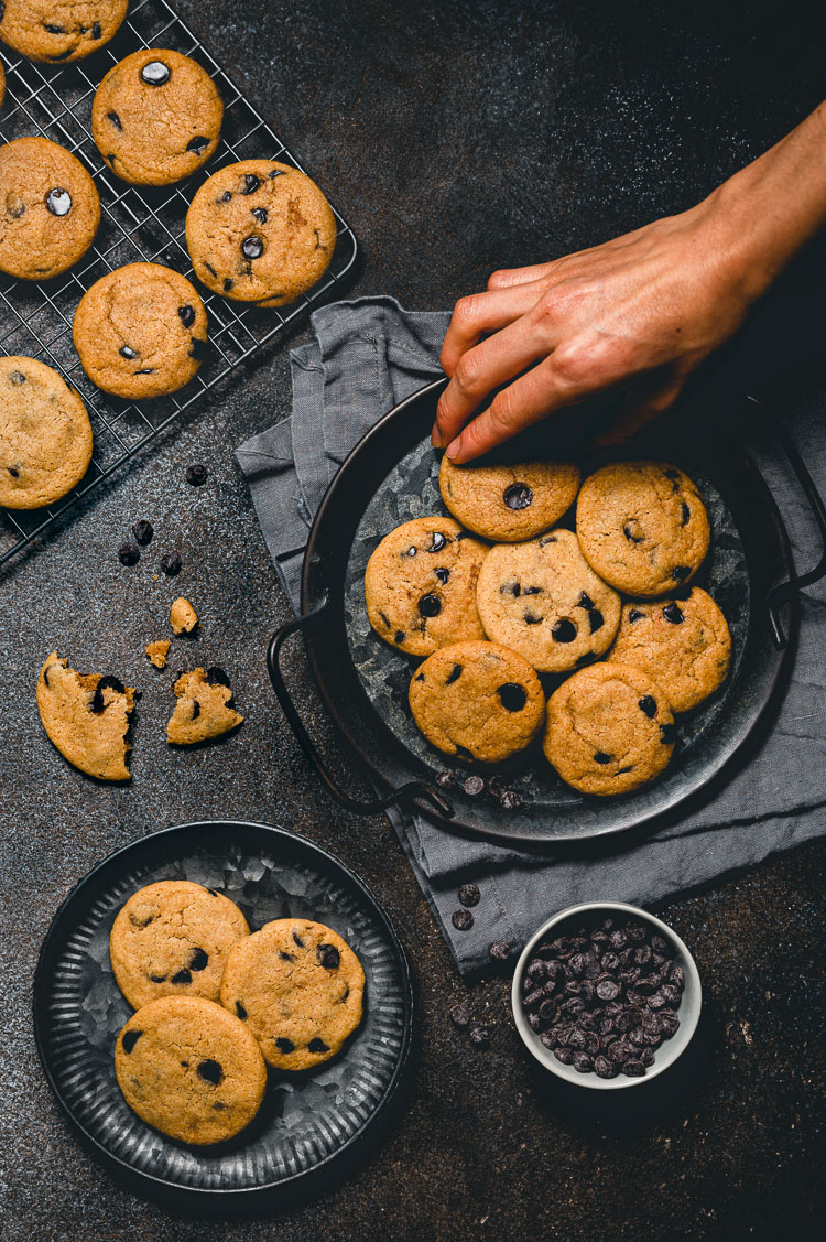 hand grabbing a chocolate chip cookie off a plate