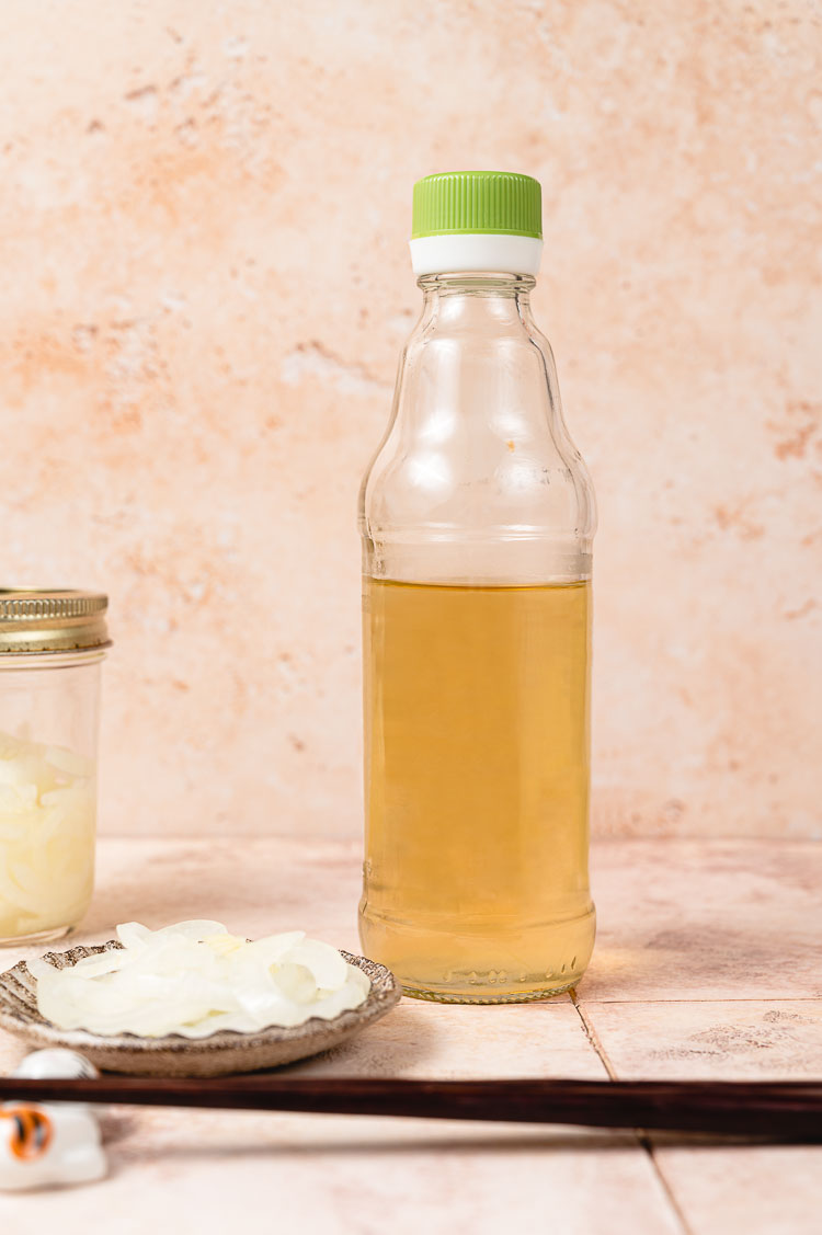 bottle of sushi vinegar next to plate of pickled onions