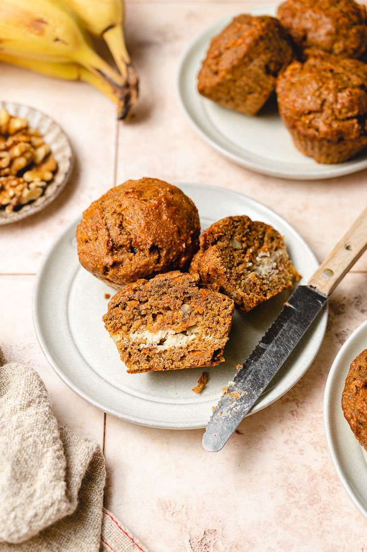 carrot cake banana muffin cut in half on a plate with knife