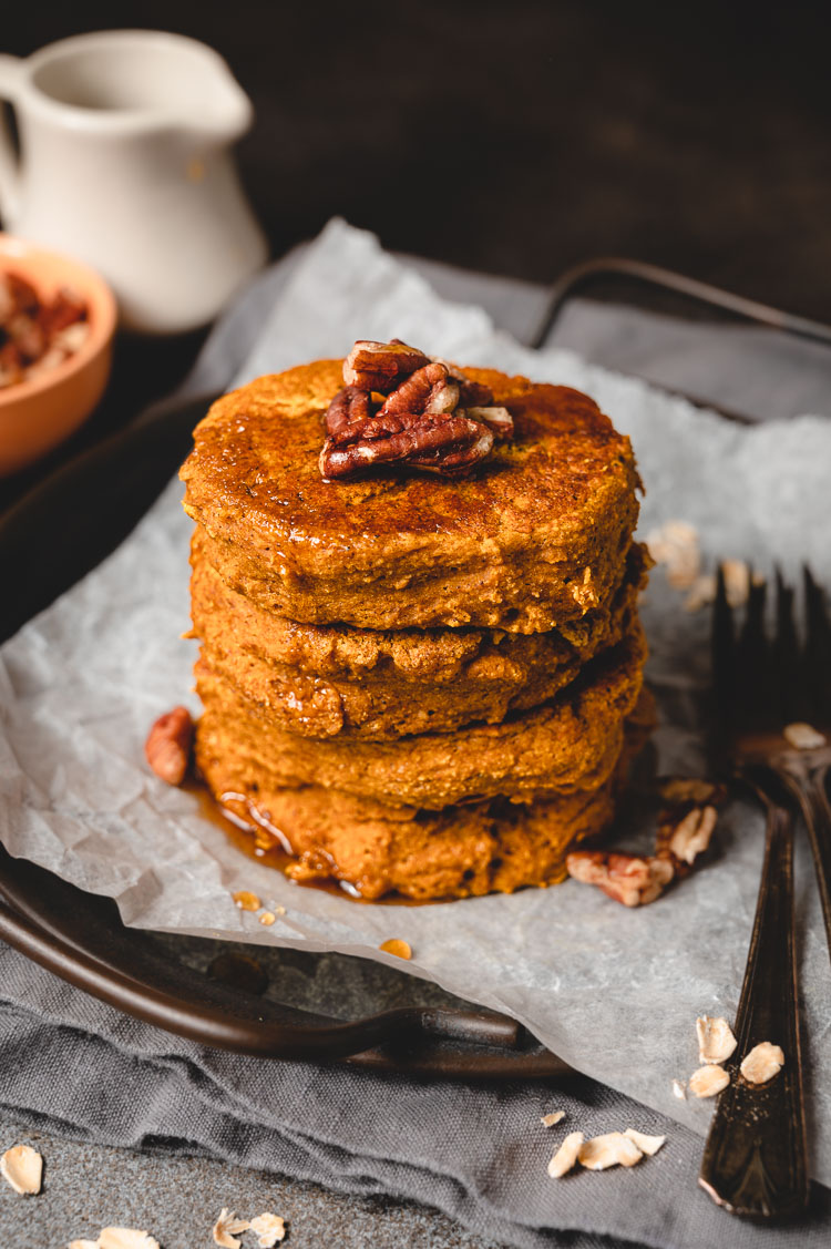 vegan pumpkin oat pancakes drizzled with maple syrup