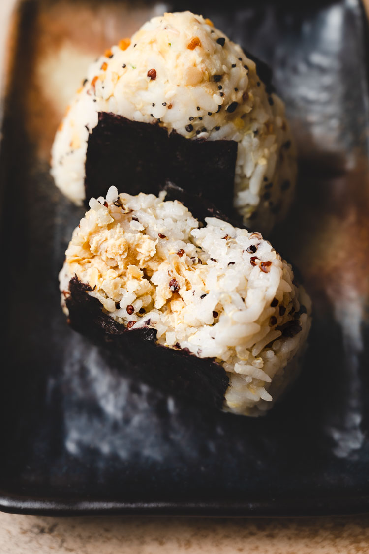 tuna mayo onigiri on a plate with a bite taken out of it