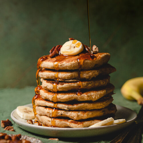 maple syrup being drizzled over vegan banana pancakes