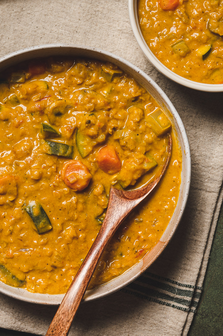 overhead view of creamy lentil curry in a bowl with spoon