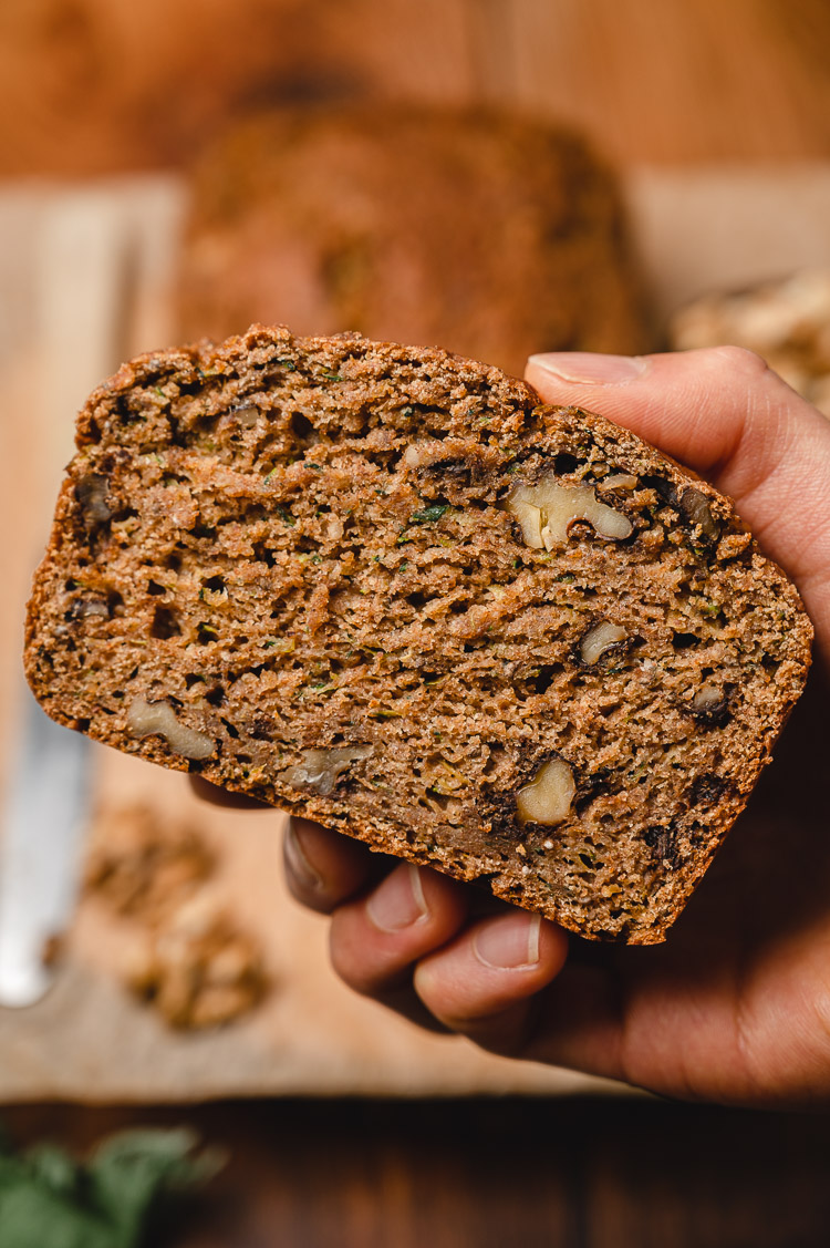 close up hand holding a slice of zucchini bread
