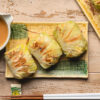 tofu cabbage rolls on a plate with peanut sauce on the side