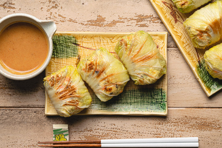 tofu cabbage rolls on a plate with peanut sauce on the side