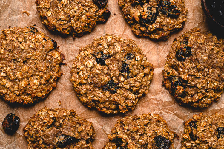 oatmeal breakfast cookies on a sheet of parchment paper with a small bowl of raisins