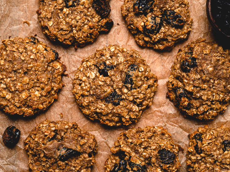 oatmeal breakfast cookies on a sheet of parchment paper with a small bowl of raisins