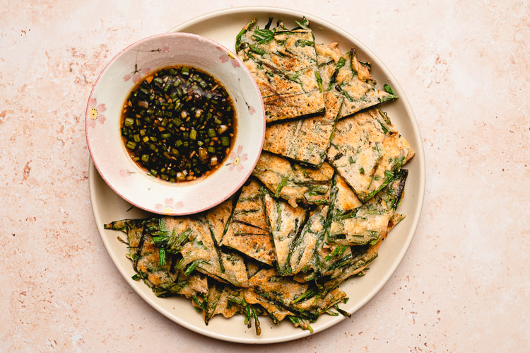 chive pancakes on a plate with dipping sauce in a bowl on the plate