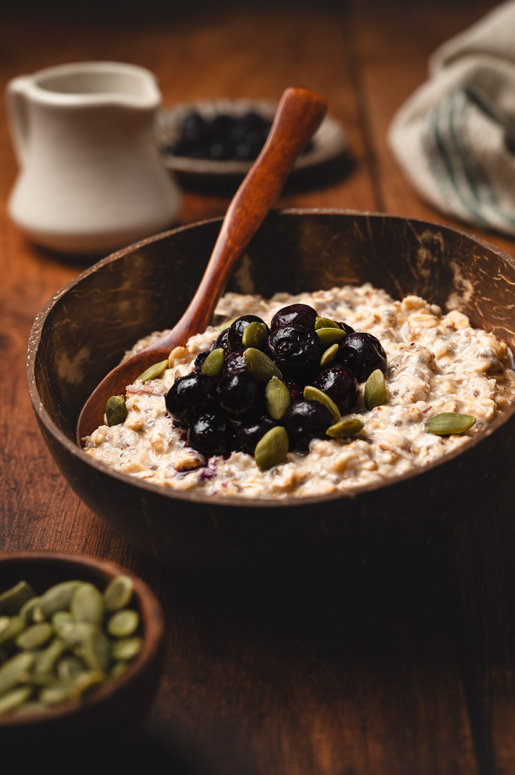 overnight oats in a bowl with spoon, topped with blueberries and pumpkin seeds