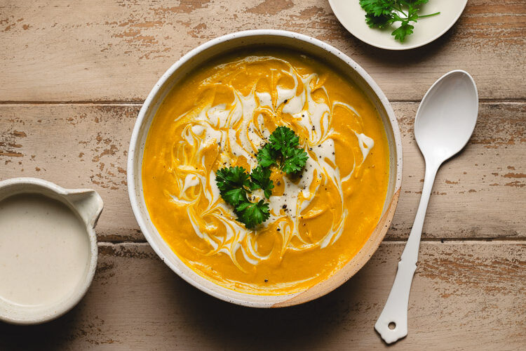 red lentil kabocha soup in a bowl topped with parsley