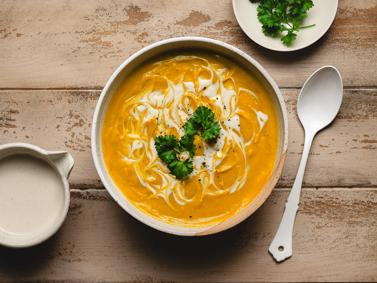 red lentil kabocha soup in a bowl topped with parsley