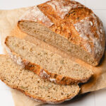 no knead bread on parchment paper, half cut into slices