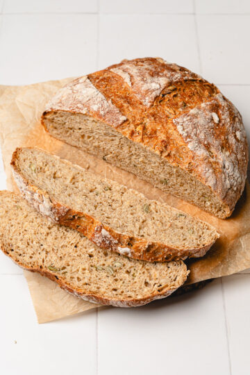 no knead bread on parchment paper, half cut into slices