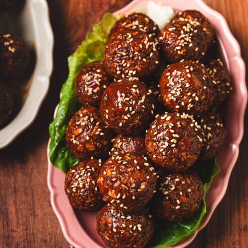 vegan sweet and sour meatballs on a plate sprinkled with sesame seeds