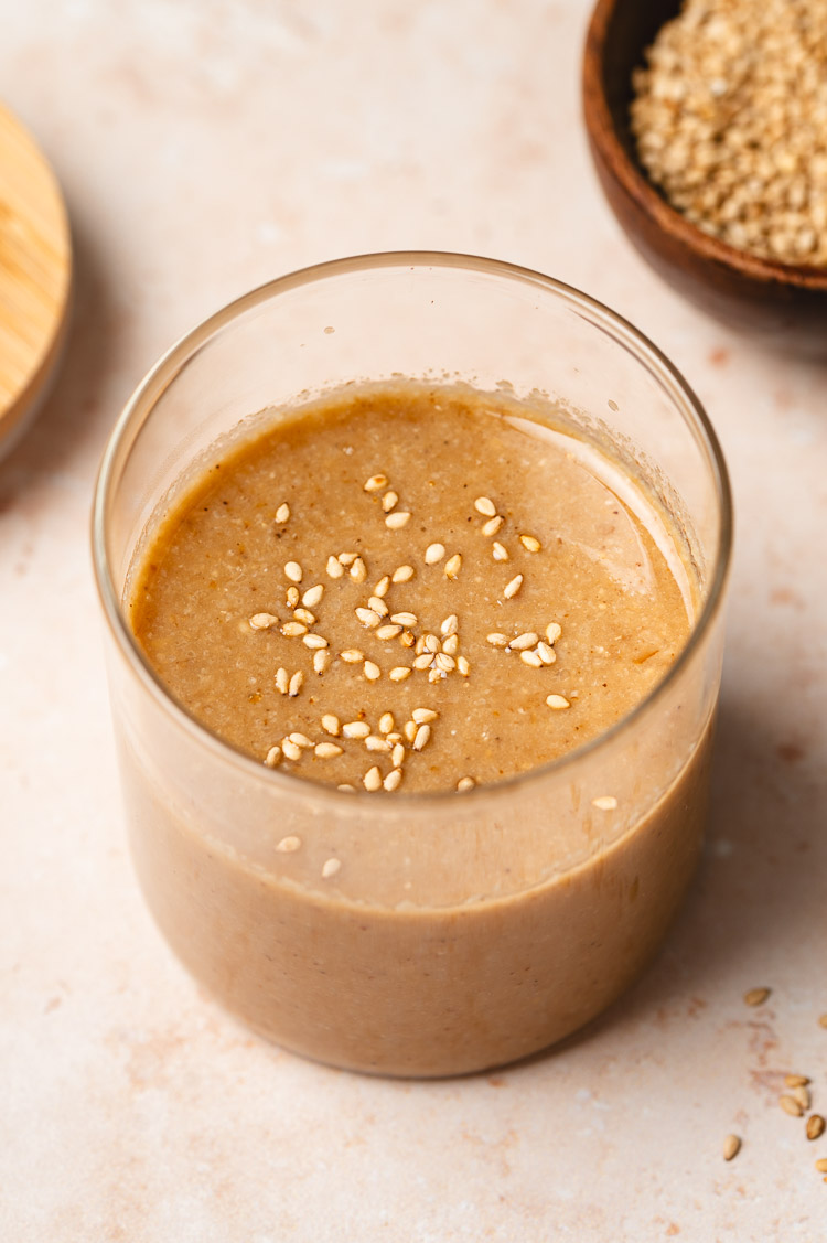 jar of japanese sesame dressing with a small bowl of sesame seeds in the corner