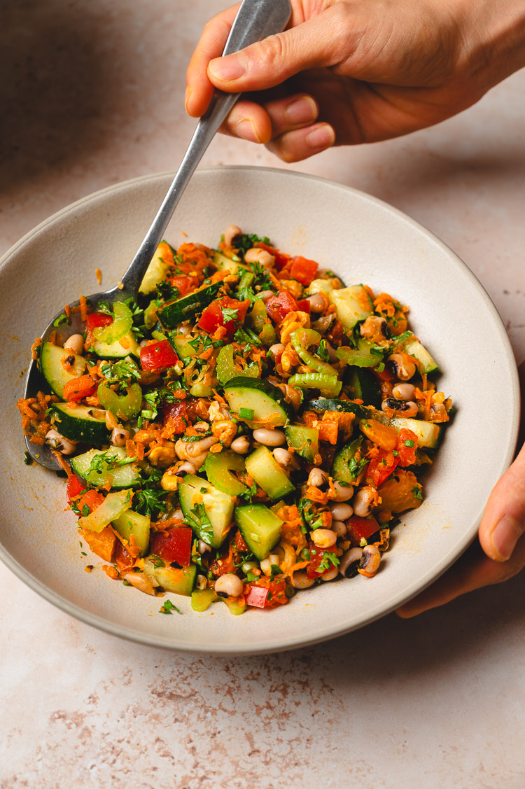 hands holding a bowl of spiced bean salad