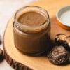 jar of homemade vegan oyster sauce surrounded by dried shiitake