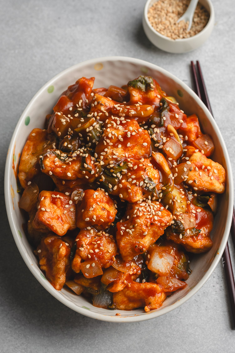 sweet and sour tofu in a bowl with chopsticks on the side